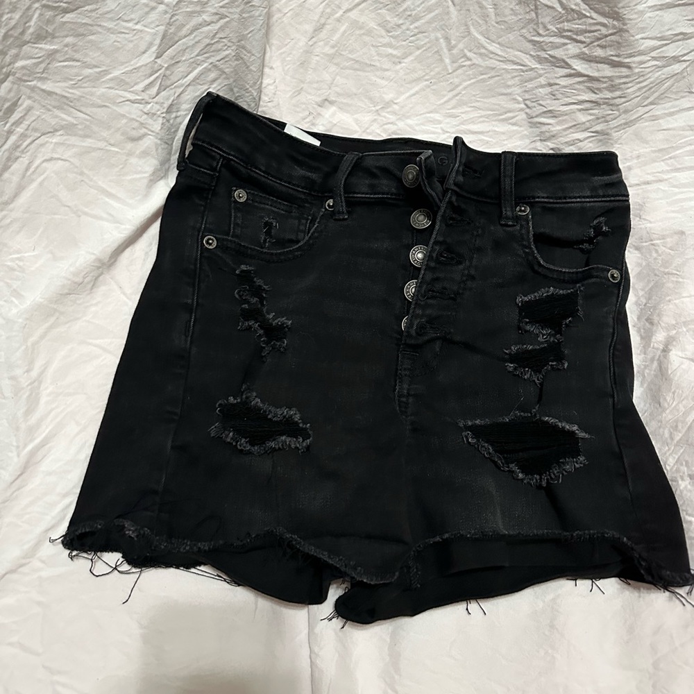 Black ripped black shorts. And with five silver buttons.